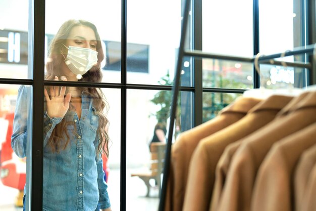 Foto donna con maschera protettiva che ammira la vetrina di un centro commerciale