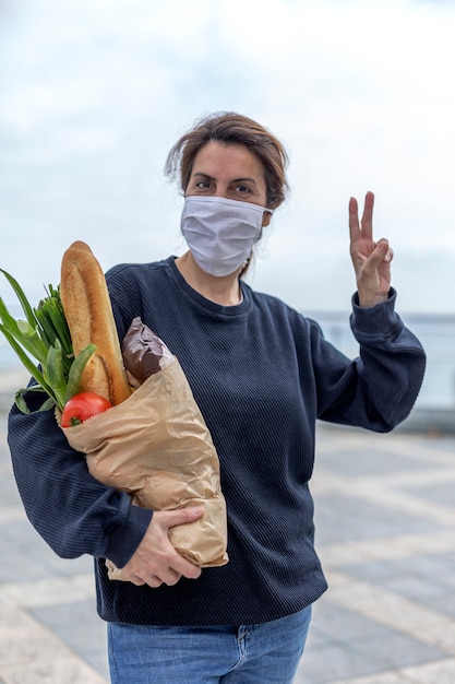 Woman in protective mask coming home with purchase