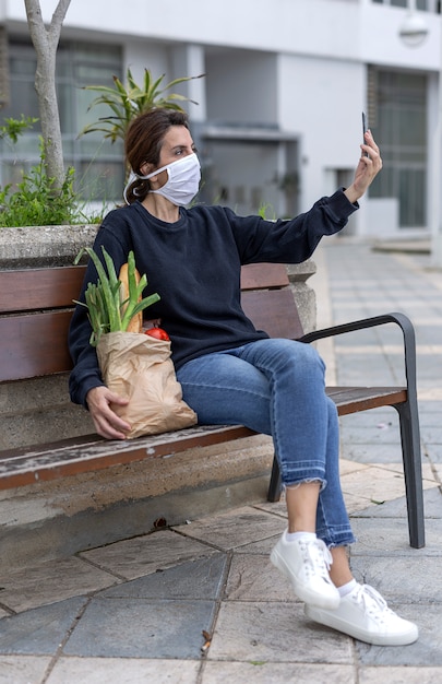 Woman in protective mask coming home with purchase