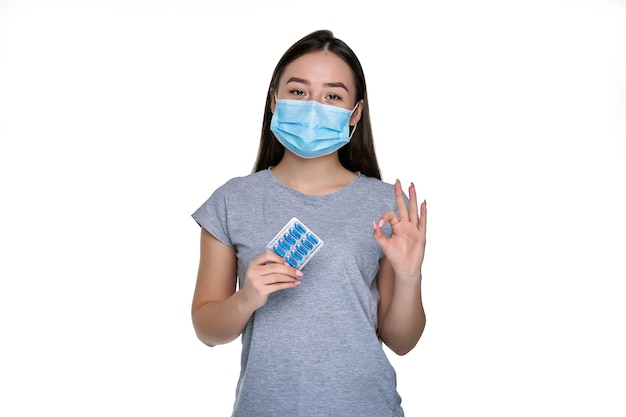 Woman in a protective mask holding pills