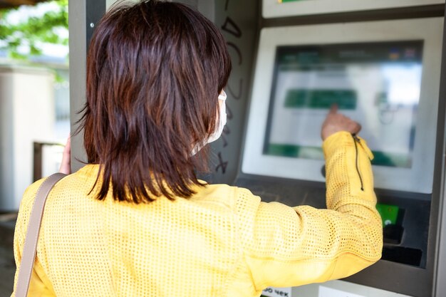 Woman in a protective mask points her finger at information board with instructions 