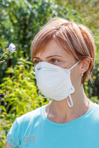 花粉に対するアレルギーと戦おうとしている保護マスクの女性。