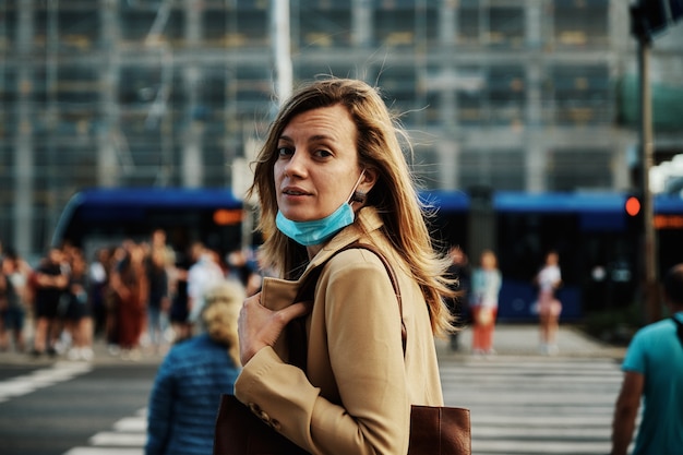 Woman in protective mask walks at city street