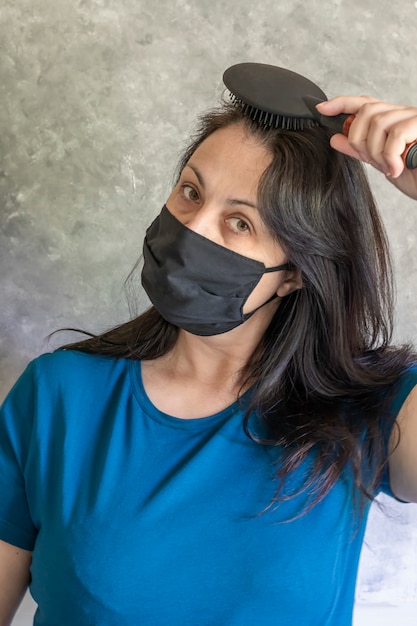 A woman in a protective medical mask communicates with her family in the kitchen. Back gray table. Remote work.