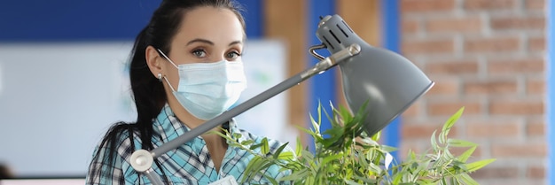 Woman in protective medical mask stands with box and personal belongings in office mass layoffs