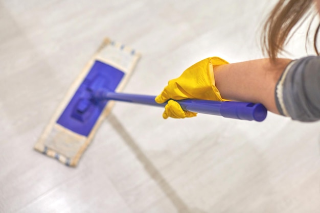 Photo woman in protective yellow rubber gloves using flat wet mop while cleaning room house cleaning