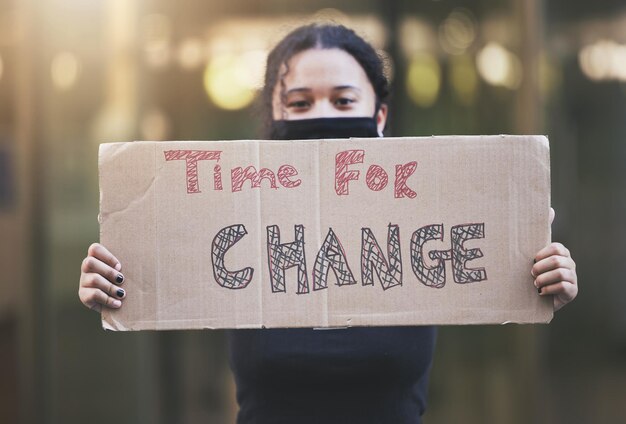 Woman protest and sign for change in human rights gender based violence or equality against a bokeh background Female activist protesting holding billboard message to voice community improvement