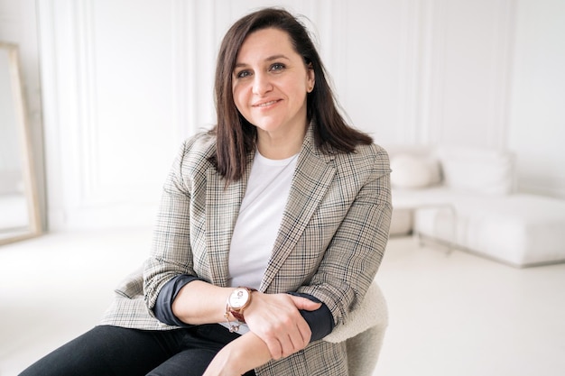 A woman psychologist in business clothes confident work in the office sitting in an armchair happy