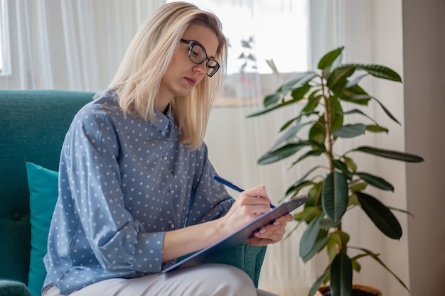 Woman psychologist or psychotherapist with eyeglasses sitting in sofa