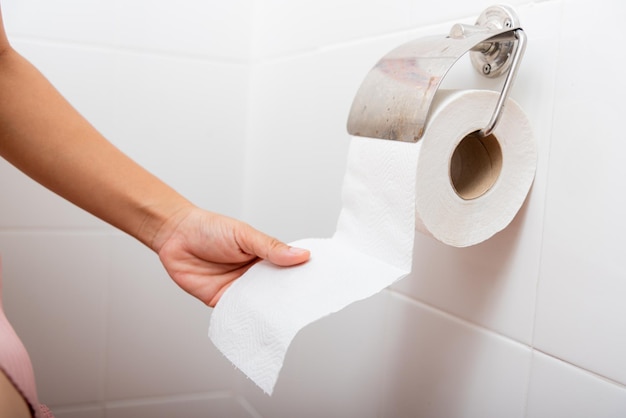 Woman pulling toilet tissue paper roll in holder for wipe