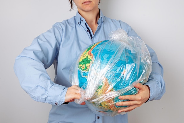 A woman pulls the earth in the form of a globe from a plastic bag the concept of environmental pollu