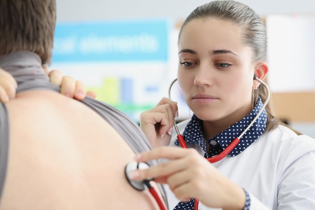 Woman pulmonologist listening to lungs of patient with stethoscope in clinic