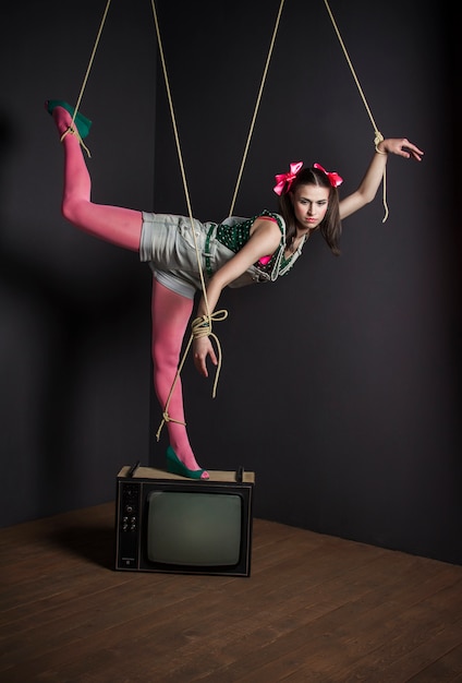 Woman puppet on TV with his hands tied posing