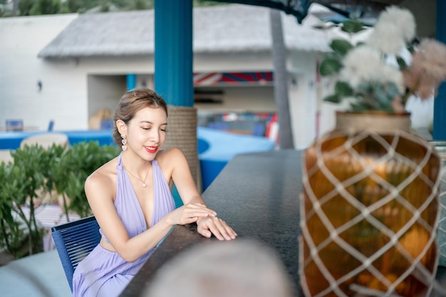 Woman in purple dress sitting on outdoor beach bar