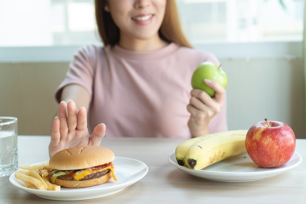 Foto la donna allontana il fast-food e sceglie la mela