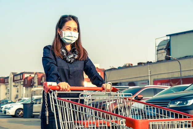 駐車場でショッピングカートを押す女性