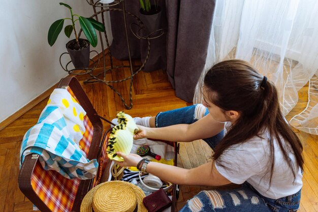 Woman put clothes in suitcase while sit on floor. preparing for trip. travel concept