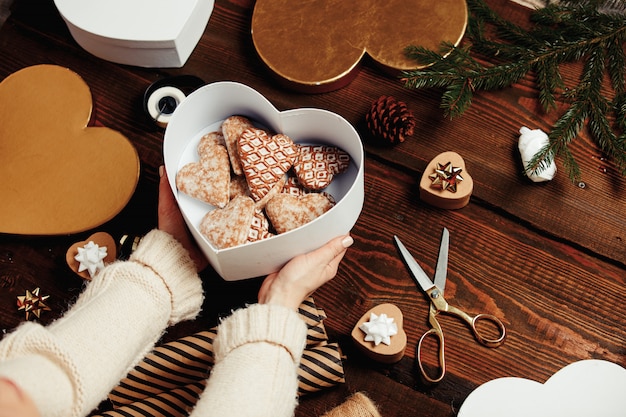 Woman put cookies in a box with gifts around