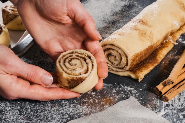 Photo woman put dough rolls on the pan and prepare buns with cinnamon for baking