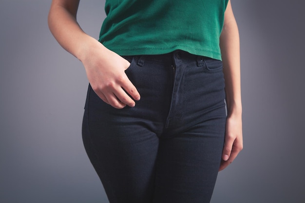 Woman put her hands on front pockets on gray background