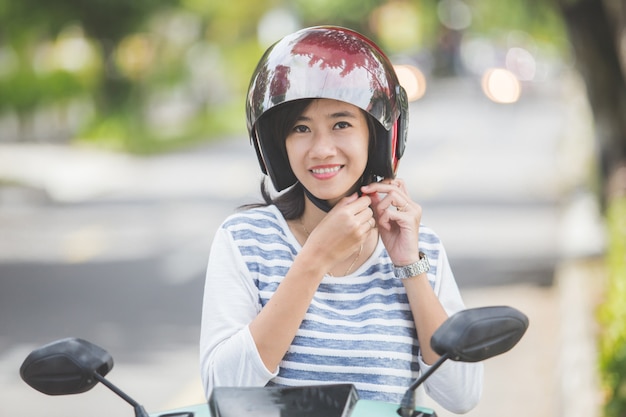 バイクに乗る前にヘルメットをかぶる女性