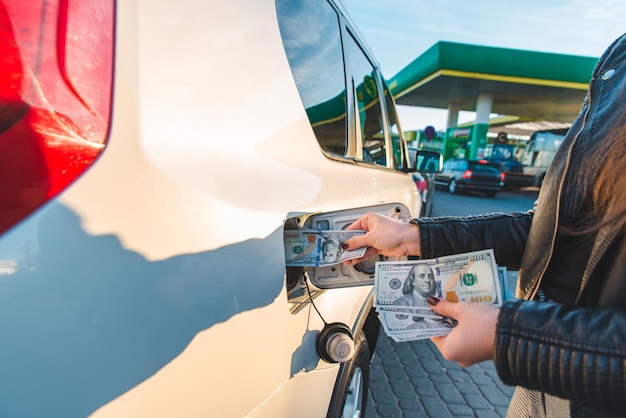 Woman put money to car tank. gasoline price hike. economy driving