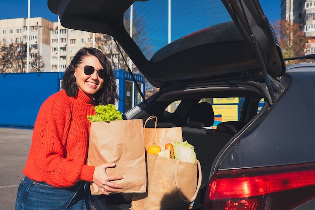 Photo woman put packages in car trunk groceries shopping