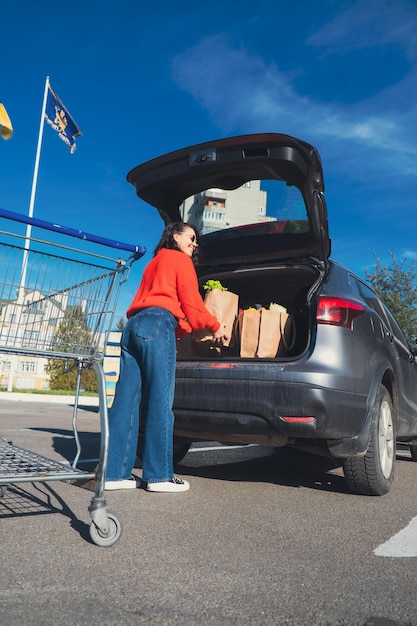 여자가 자동차 트크에 패키지를 넣고 식료품 쇼핑을 합니다.