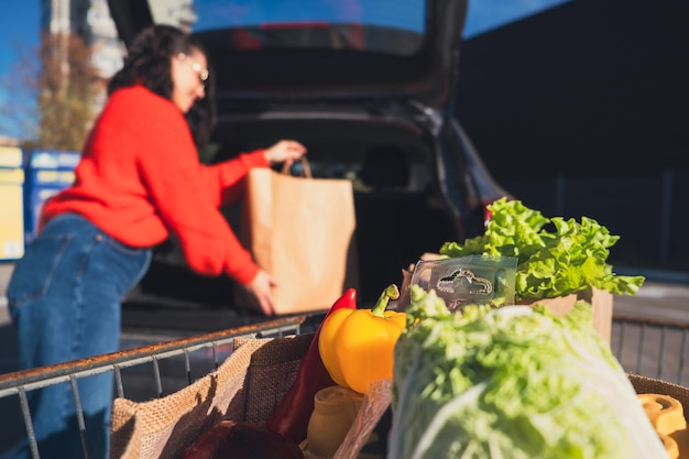 woman put packages in car trunk groceries shopping