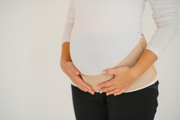 Woman puts on a bandage for pregnant women. Close-up.