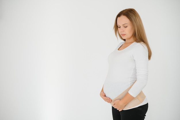 Woman puts on a bandage for pregnant women. Close-up.