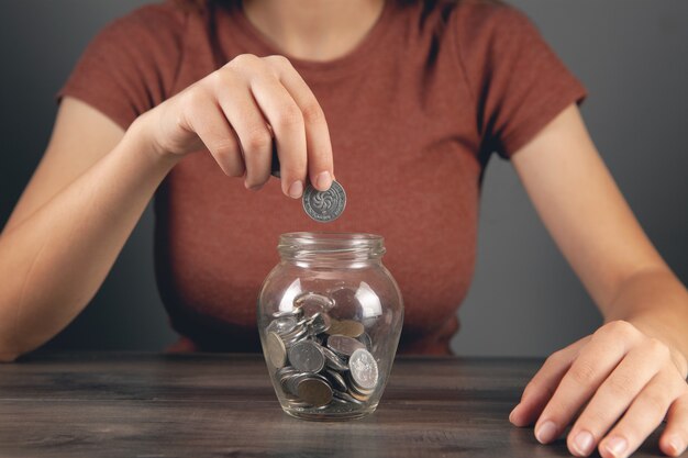 A woman puts a coin in a savings jar