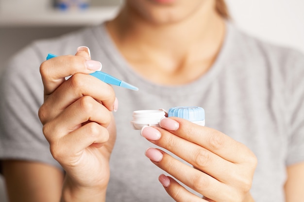 Woman puts on a contact lens for vision correction