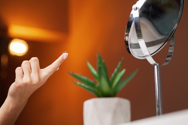 Woman puts on a contact lens for vision correction