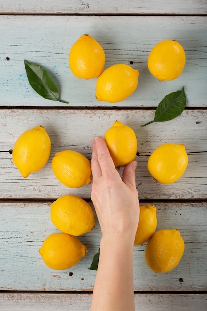 Woman puts Fresh fragrant lemons on a blue wooden table