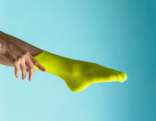 woman puts green socks on her feet. Isolated on white background