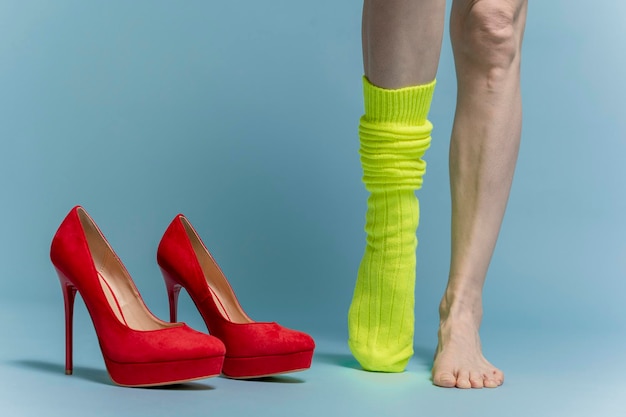 woman puts on green socks. isolated on blue background