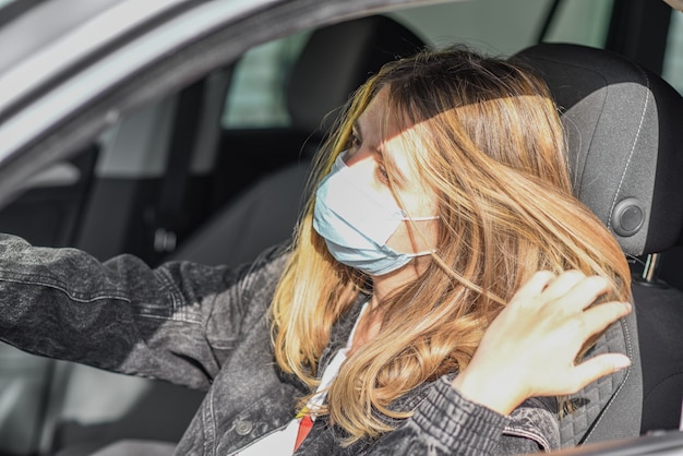 여자는 자동차에서 운전하기 전에 보호 마스크를 착용