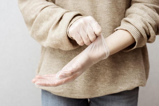 Woman puts on rubber gloves to protect her hands