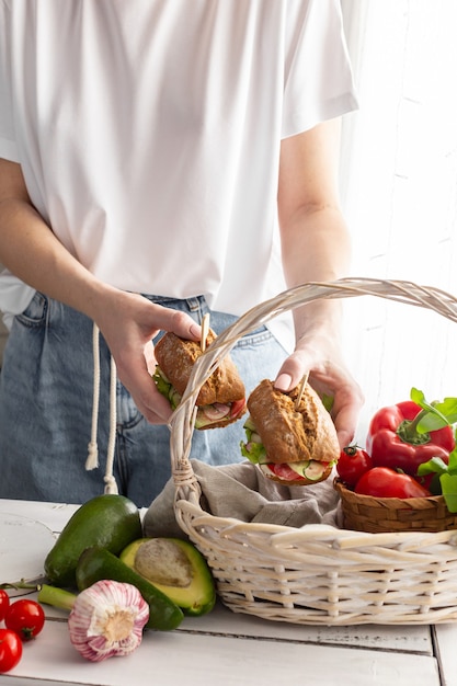 Woman puts sandwiches in a picnic basket