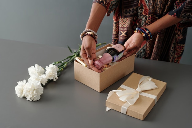 Photo woman putting champagne into box