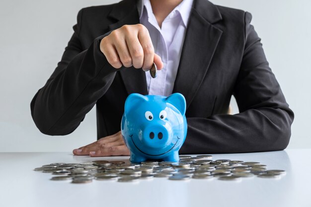 Woman putting coin in blue piggy bank