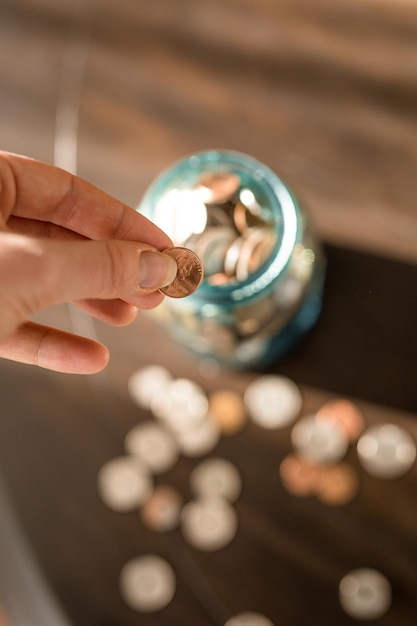 Photo woman putting coins into jar saving money penny pinching