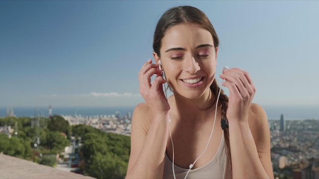 Photo woman putting on earphones in city of barcelona girl listening music in earbuds