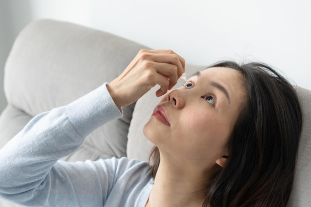 写真 自宅のソファに座って眼液を注ぐ女性