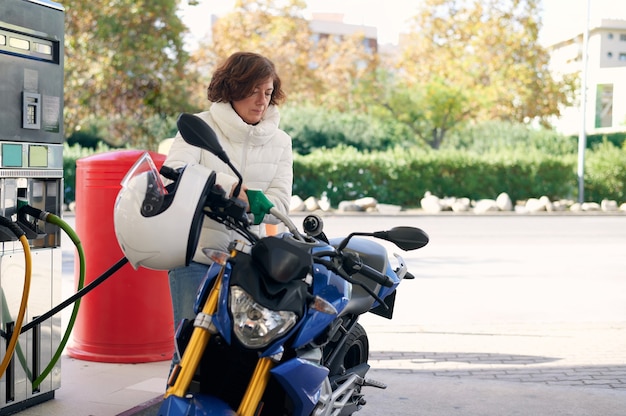 Женщина заправляет свой мотоцикл бензином