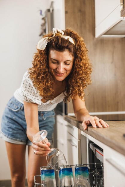 Photo a woman putting glass in a dishwasher