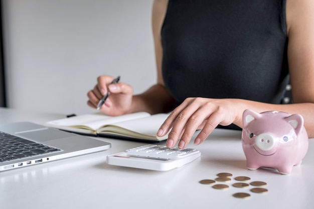 Woman putting golden coin in pink piggy bank for step up growing business to profit and saving with piggy bank, Saving money for future plan and retirement fund concept