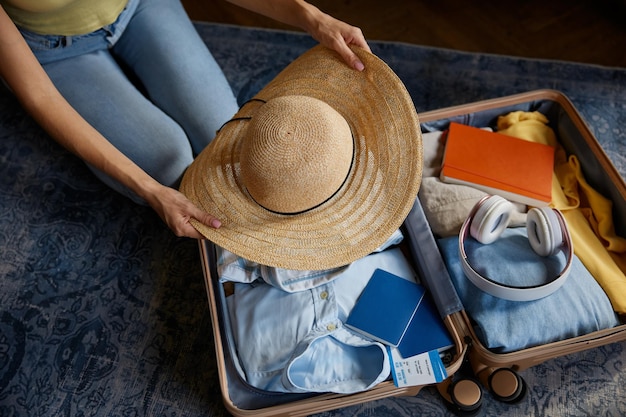 女性が夏の服を履いた旅行袋に帽子をかぶっている