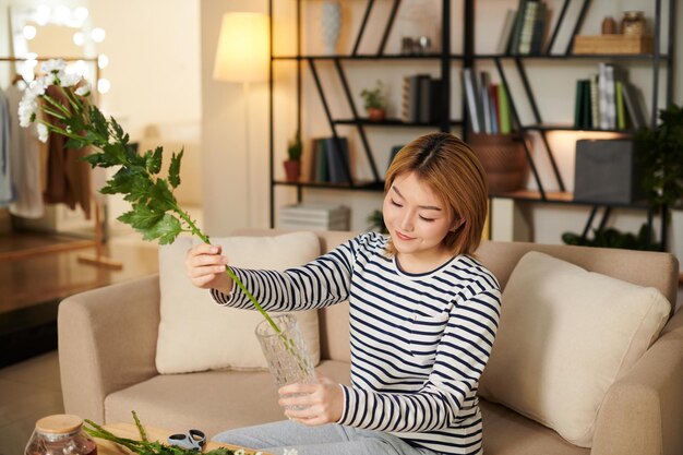 꽃병에 잎이 많은 줄기를 넣는 여자